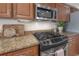 Close-up of kitchen gas range with granite countertops and ample cabinet space with stainless steel microwave above at 13906 Captains Reef Ct, Tampa, FL 33624