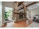 Living room featuring a stone fireplace, exposed beams, hardwood floors, and a large window at 13906 Captains Reef Ct, Tampa, FL 33624