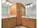 Bathroom with wood vanity featuring double sinks and large mirrors at 14537 Mirabelle Vista Cir, Tampa, FL 33626