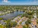 An aerial view shows houses surrounding a lake within a neighborhood full of mature trees and green landscaping at 1501 84Th N Ave, St Petersburg, FL 33702