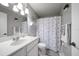 Well-lit bathroom featuring a neutral color scheme and a shower with a floral curtain at 1715 Belleair Forest Dr # C, Belleair, FL 33756