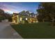 Exterior twilight view of a beautiful home with lush lawn, mature trees, and an illuminated driveway at 18929 Crescent Rd, Odessa, FL 33556