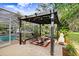 Screened lanai with covered pergola, outdoor seating, pool, and lush landscaping for tranquil backyard relaxation at 18929 Crescent Rd, Odessa, FL 33556