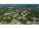 Real estate aerial view of a home in a wooded neighborhood with several other single Gathering homes and a commercial area nearby at 2167 Corfell St, Port Charlotte, FL 33948