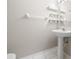 Clean bathroom with a pedestal sink, mirror, open shelving, and white tiled floors at 2306 Lake Woodberry Cir, Brandon, FL 33511