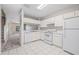 Clean kitchen featuring white appliances, ample cabinet space, and tiled flooring with stairs leading upstairs at 2306 Lake Woodberry Cir, Brandon, FL 33511