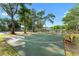 Outdoor basketball court with bench seating surrounded by mature shade trees and landscaping at 2373 Hounds Trl, Palm Harbor, FL 34683