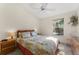 Cozy bedroom with a ceiling fan, large window, and a bed with colorful, patterned linens at 2373 Hounds Trl, Palm Harbor, FL 34683