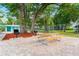 Outdoor picnic area featuring a grill, table and benches on a brick patio under mature trees at 2373 Hounds Trl, Palm Harbor, FL 34683