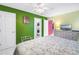Bright bedroom with colorful walls, ceiling fan, dresser with TV, and an interior laundry closet with stacked washer and dryer at 250 Medallion Blvd # H, Madeira Beach, FL 33708