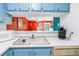 Bright kitchen with white countertops, blue cabinetry and appliances, and pass-through to the living room at 250 Medallion Blvd # H, Madeira Beach, FL 33708
