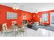 Bright living room with vibrant red walls, ceiling fans, a glass table, and access to the outdoor space at 250 Medallion Blvd # H, Madeira Beach, FL 33708