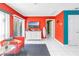 Comfortable living room featuring vibrant red walls, white tile flooring, and access to the balcony at 250 Medallion Blvd # H, Madeira Beach, FL 33708