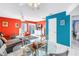 Bright living room and dining area with vibrant red walls, white tile flooring, and access to the balcony at 250 Medallion Blvd # H, Madeira Beach, FL 33708
