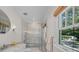 Elegant bathroom featuring a glass shower, marble tile, and a round mirror at 2523 W Sunset Dr, Tampa, FL 33629