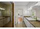 Bathroom with granite counters, white cabinets, glass shower, and natural stone floor tiles at 2523 W Sunset Dr, Tampa, FL 33629