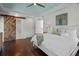 Main bedroom with tray ceiling, hardwood floors, and a decorative sliding barn door to the bathroom at 2523 W Sunset Dr, Tampa, FL 33629