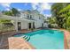 Beautiful pool area with brick paving and a charming two-story home in the background at 2523 W Sunset Dr, Tampa, FL 33629