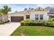Inviting single-story home with a well-kept lawn, a brown garage door, and landscaped shrubs at 2644 Leafwing Ct, Palm Harbor, FL 34683