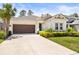 Charming single-Gathering home featuring a well-manicured lawn and a brown two-car garage at 2644 Leafwing Ct, Palm Harbor, FL 34683