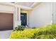Close up of the covered entry with a blue front door and yellow bushes at 2644 Leafwing Ct, Palm Harbor, FL 34683