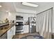 Bright kitchen featuring stainless steel appliances, white cabinetry, and an adjacent window with light-filtering curtains at 310 S Delaware Ave # F, Tampa, FL 33606