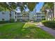 Inviting condo building with lush landscaping, a sidewalk, and palm trees creates an appealing outdoor space at 330 Promenade Dr # 206, Dunedin, FL 34698