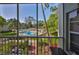 Balcony view overlooking the community pool area, surrounded by lush greenery, from behind a screened patio at 330 Promenade Dr # 206, Dunedin, FL 34698