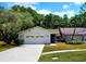 Charming single-story home featuring a two-car garage, well-manicured lawn, and beautiful mature trees at 3529 Tanglewood Trl, Palm Harbor, FL 34685