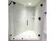 Modern bathroom shower featuring glass doors, a rainfall shower head and marble-patterned walls at 3529 Tanglewood Trl, Palm Harbor, FL 34685