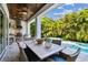 Outdoor kitchen and dining area with wood ceiling, view of the pool, and lush tropical landscaping at 3905 W San Obispo St, Tampa, FL 33629