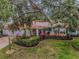 Charming single-story home featuring a colorful exterior, lush landscaping, and mature trees at 40 Pine Lake Dr, Oldsmar, FL 34677