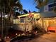 Charming coastal home exterior with manicured landscaping, illuminated by landscape lighting at 412 80Th St, Holmes Beach, FL 34217