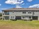 Eye-level view of the back exterior of modern townhomes with screened-in lanais and lush lawns at 4828 San Martino Dr, Wesley Chapel, FL 33543