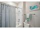 Bathroom with a shower and tub combo behind a patterned shower curtain and beach themed artwork at 4828 San Martino Dr, Wesley Chapel, FL 33543