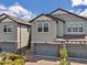 Close-up view of a modern townhome featuring a two-car garage, decorative stone accents, and well-kept landscaping at 4828 San Martino Dr, Wesley Chapel, FL 33543