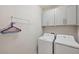 Functional laundry room with gray cabinets and white washer and dryer for added convenience at 4828 San Martino Dr, Wesley Chapel, FL 33543
