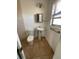 Compact bathroom with a pedestal sink, toilet, mirror, and window, featuring neutral tiling and fixtures at 7421 Mulligan Ct, Port Richey, FL 34668