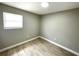 A modestly styled bedroom with wood-look tile floors and a single window at 8310 Croton Ave, Tampa, FL 33619