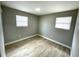 A simply styled bedroom offers wood-look tile flooring and light gray walls with two windows at 8310 Croton Ave, Tampa, FL 33619