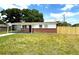 A cozy one-story house showcasing a new wooden fence, brick facade, and a green lawn at 8310 Croton Ave, Tampa, FL 33619
