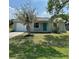 Charming single-story home featuring a well-maintained lawn, front yard tree, and a bright blue front door at 9230 Wood Dr, Hudson, FL 34667