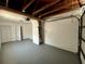 Spacious garage with exposed ceiling beams, fresh paint, and an overhead door at 9230 Wood Dr, Hudson, FL 34667