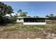 Back of the property featuring a screened-in porch and an expansive yard space at 9230 Wood Dr, Hudson, FL 34667