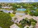 An aerial view of condos surrounded by trees, and a pond between a home and two tennis courts at 1015 S Pointe Alexis Dr, Tarpon Springs, FL 34689