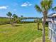 Expansive backyard with manicured lawn, swaying palm trees, and stunning lake views offering a tranquil setting at 1015 S Pointe Alexis Dr, Tarpon Springs, FL 34689