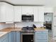 Kitchen showcasing white upper cabinets and blue lower cabinets with wood countertops at 1015 S Pointe Alexis Dr, Tarpon Springs, FL 34689