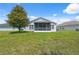 View of the home's backyard with a screened-in porch, lush lawn, and mature tree at 11220 Godwit Ct, New Port Richey, FL 34654