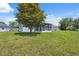 View of the home's backyard with a screened-in porch, lush lawn, and mature tree at 11220 Godwit Ct, New Port Richey, FL 34654