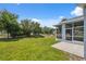 The screened lanai overlooks a spacious backyard with green grass and mature shade trees at 11220 Godwit Ct, New Port Richey, FL 34654